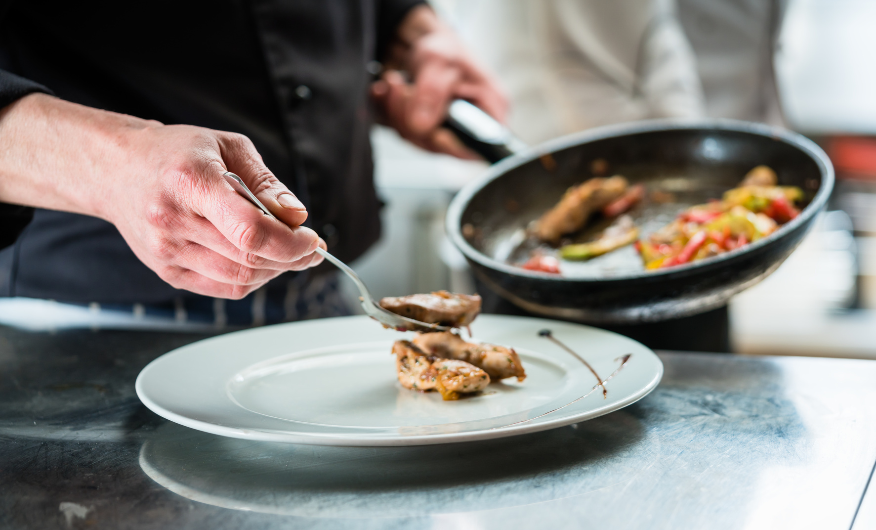 Un cuisinier dresse un plat de volaille