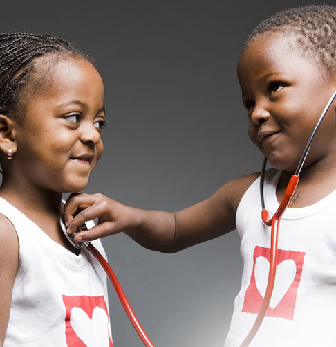 Deux enfants avec des tee-shirt ayant le logo de Mécénat Chirurgie Cardiaque jouant au docteur