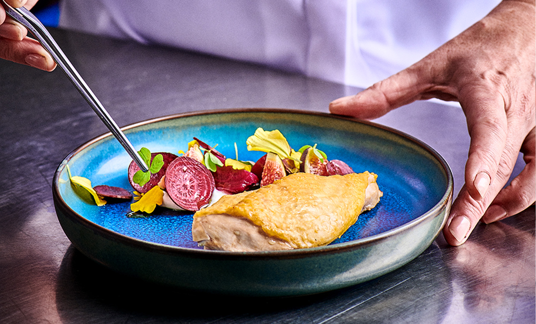 Un cuisinier dresse un plat de volaille